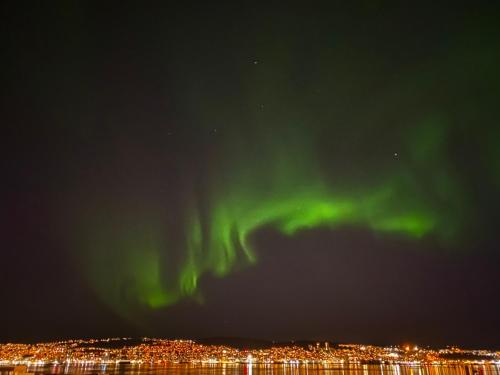 an aurora in the sky over a city at Polar Arctic View - Free Parking! in Tromsø