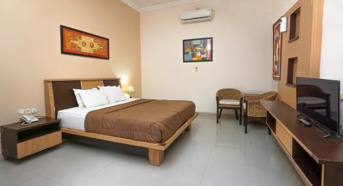 ein Hotelzimmer mit einem Bett und einem TV in der Unterkunft Musdalifah Hotel in Nambakor