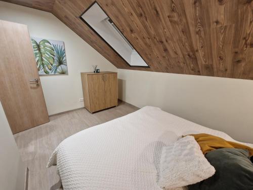 um quarto com uma cama branca e um tecto de madeira em Apartmány “Chaty Krušetnica “ em Krušetnica