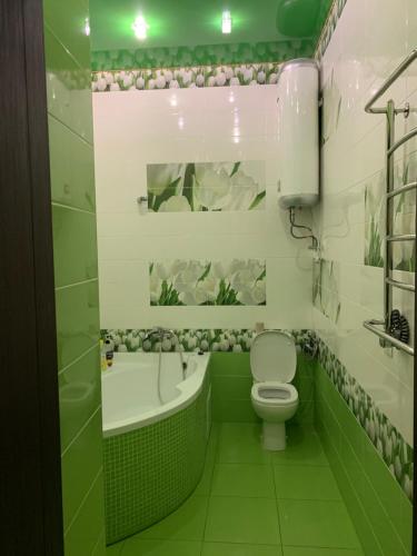a green bathroom with a toilet and a bath tub at 2-х комн квартира в новом элитном доме в центральном районе города in Cherkasy
