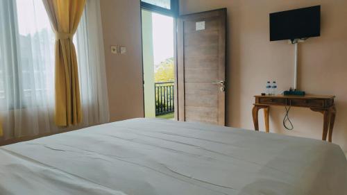 um quarto com uma grande cama branca e uma janela em PURNAMA HOUSE KUTA em Kuta