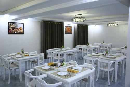 un comedor con mesas blancas y sillas blancas en CITIZEN HOTEL, en Nukus