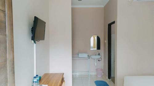 a bathroom with a sink and a tv on a wall at PURNAMA HOUSE KUTA in Kuta