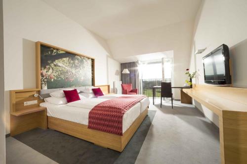 Schlafzimmer mit einem Bett und einem Flachbild-TV in der Unterkunft Hotel Staribacher Südsteiermark in Leibnitz