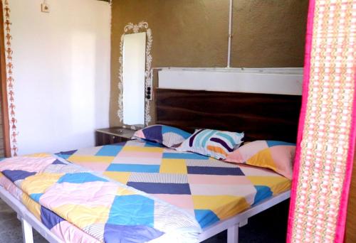 a bed with a colorful comforter in a bedroom at Tarangini Farmstay in Maheshwar