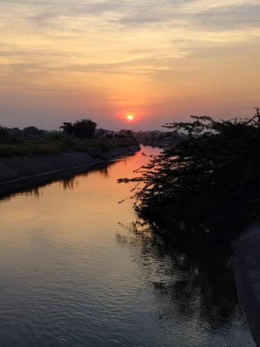 a river with the sun setting in the distance at Tarangini Farmstay in Maheshwar