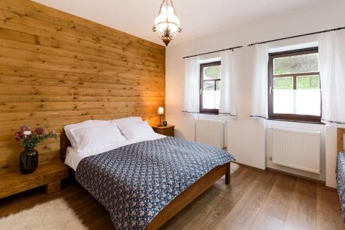 1 dormitorio con una pared de madera y 1 cama en Elizabeth Cottage Benczúrfalva, en Szécsény