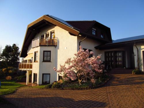 a white building with a balcony and a tree at Schmidt`s Eppelborner Ferienwohnung in Eppelborn