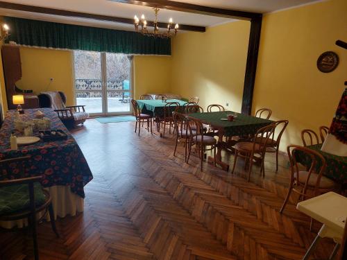 une salle à manger avec des tables et des chaises ainsi qu'une grande fenêtre dans l'établissement Willa Słotwinka, à Krynica-Zdrój