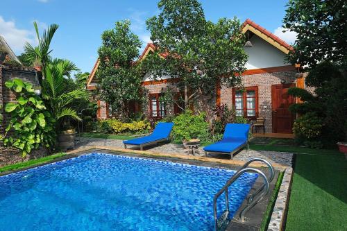 - une piscine avec 2 chaises bleues à côté d'une maison dans l'établissement Tamcoc Mr. Cau Homestay, à Ninh Binh