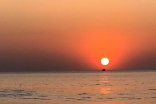 a sunset over the ocean with a rock in the water at Kedige Homestay in Kumta