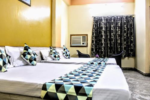 2 Betten in einem Hotelzimmer mit Fenster in der Unterkunft Maruti Group of Hotels - Shree Ram Darshan in Nāthdwāra