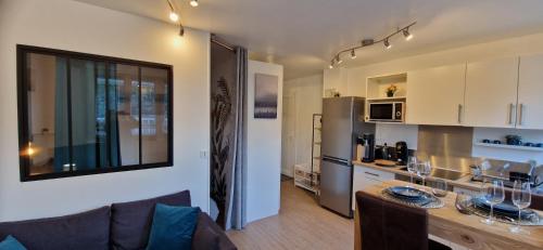 a kitchen and a living room with a couch and a table at Beau studio très calme, parking privée gratuit, Netflix in Linas