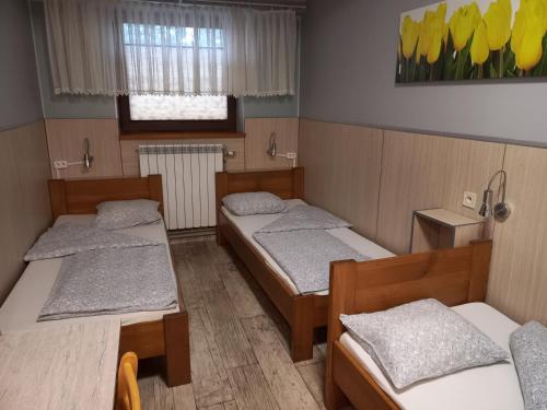 trzy łóżka w pokoju z żółtymi tulipanami na ścianie w obiekcie Pokoje Gościnne Jaga w Kielcach