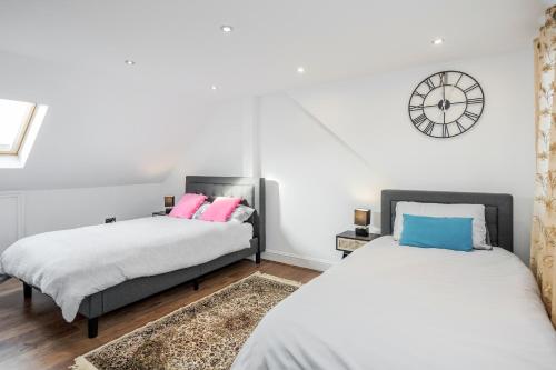 duas camas num quarto com um relógio na parede em Entire Lovely family home with Wi-Fi, Netflix, self check-in em Londres