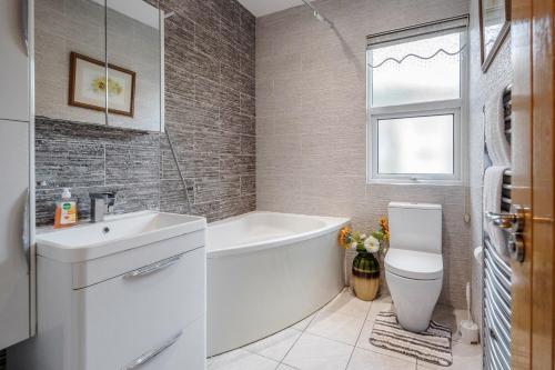 uma casa de banho com uma banheira, um lavatório e um WC. em Entire Lovely family home with Wi-Fi, Netflix, self check-in em Londres