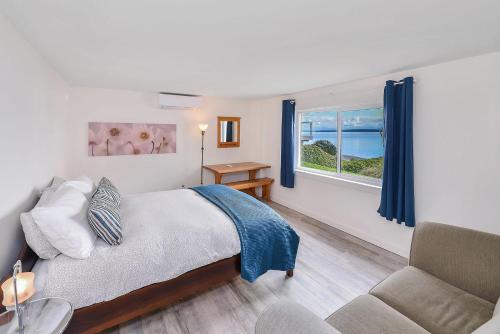 a bedroom with a bed and a couch and a window at Bazan Bay Beach House in North Saanich