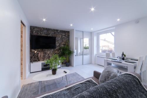 a living room with a couch and a stone wall at LE ROYAL SWEET - PARKING GRATUIT + WIFI in Mulhouse