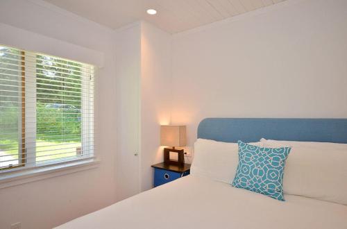 a white bedroom with a bed and a window at Pendray House in North Saanich