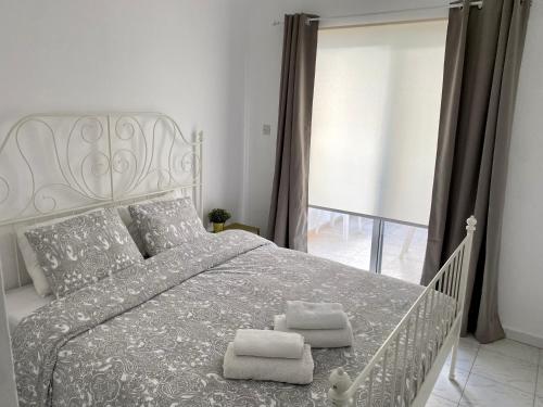 a bedroom with a white bed with two towels on it at Kontheo Elli Ground Apt 2 near the beach in Larnaka