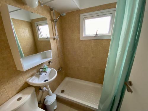a bathroom with a sink and a toilet and a mirror at Kontheo Elli Ground Apt 2 near the beach in Larnaka