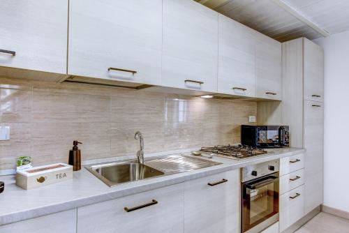 a kitchen with white cabinets and a stainless steel sink at Luminoso appartamento nel cuore di Genova+balcone in Genova