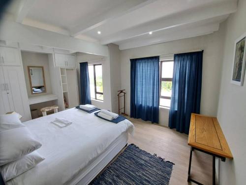 a bedroom with a large white bed with blue curtains at Angel's Rest in Port Alfred