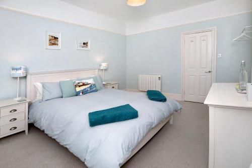 a bedroom with a white bed with a green towel on it at Seaview at No. 26 Northumberland Place in Teignmouth