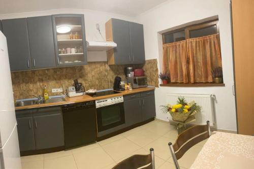 a kitchen with gray cabinets and a sink and a table at Vila primitoare in apropiere de aeroport in Ghiroda