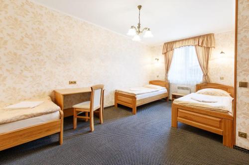 a room with three beds and a table and chairs at LIONS Nesuchyně 