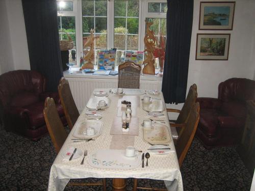 una sala da pranzo con tavolo, sedie e finestra di Four seasons Guest House a Pembrey