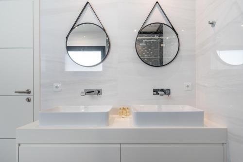 Baño blanco con 2 lavabos y espejo en Villa das Amendoeiras by HelloVacations, en Albufeira