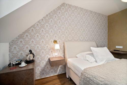 a small bedroom with a bed and a wall at Hotel MAXPLAZA in Trnava