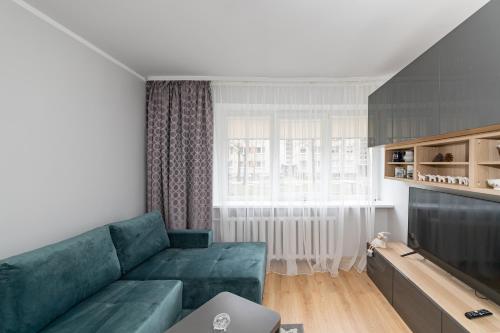 ein Wohnzimmer mit einem grünen Sofa und einem TV in der Unterkunft Modern n' lovely apartment by Polo Apartments in Kaunas