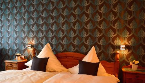 um quarto com uma cama com almofadas e um papel de parede em Gästehaus des Haus Krone em Bexbach