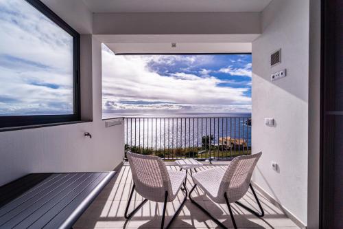 een balkon met 2 stoelen, een tafel en een groot raam bij Guesthouse Olival in Santa Cruz