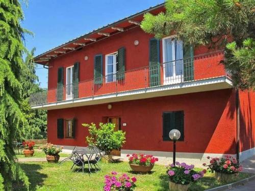 Casa roja con balcón y algunas flores en Villa Sissi, en Arliano