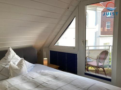 a bedroom with a bed and a window with a chair at Haus Atelier Appartement 101 - Wohnung 4 in Juist