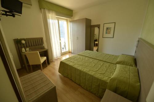 a bedroom with a green bed and a desk at Hotel Villa Florida in Malcesine