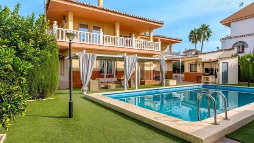 a villa with a swimming pool in front of a house at Villa de la Acacia in Gójar