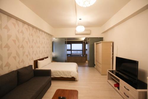 a living room with a bed and a couch and a television at 晨曦溫泉宅 in Toucheng
