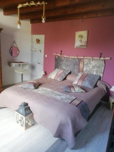 - une chambre avec un grand lit aux murs roses dans l'établissement Les Amandiers de Jade, à Saint-Agnet