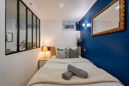 パリにあるElegant and cosy 2/3 rooms - Heart of Parisの青と白のベッドルーム(ベッド1台、鏡付)