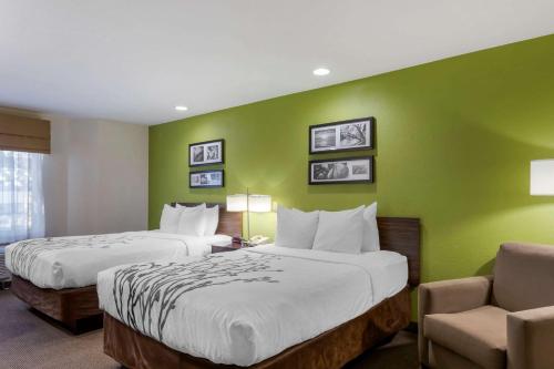 2 camas en una habitación de hotel con paredes verdes en Sleep Inn Ontario, en Ontario