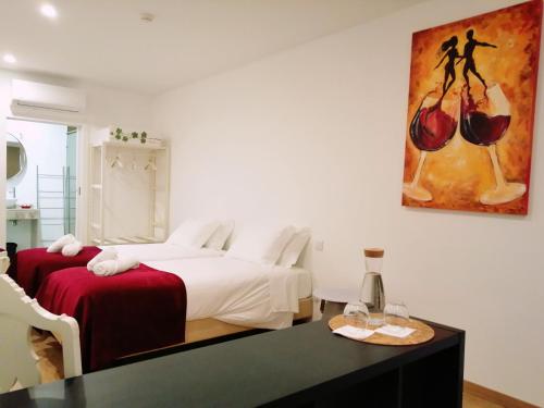 a bedroom with two beds and a table and a painting at Gamboas Place in Olhalvo