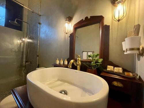 ein Badezimmer mit einer großen Badewanne und einem Spiegel in der Unterkunft Rosewood Manor in Botiyatenna