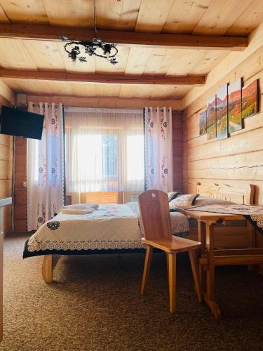 a bedroom with a bed and a table and a chair at U Maćka in Poronin