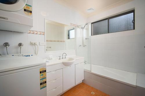 een witte badkamer met een wastafel en een spiegel bij Hornsby Furnished Apartments in Hornsby