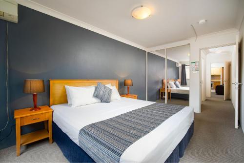 een slaapkamer met een groot bed met een blauwe muur bij Hornsby Furnished Apartments in Hornsby