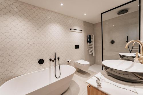 a bathroom with a tub and a sink and a toilet at Strandhotel Kurhaus Juist in Juist